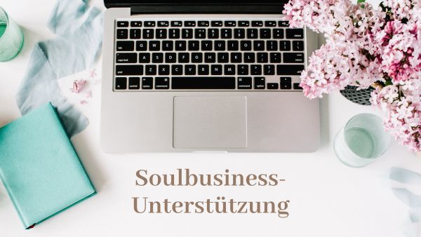 ein femininer Schreibtisch mit Laptop und Blumen und der Bezeichnung Soulbusiness Unterstützung